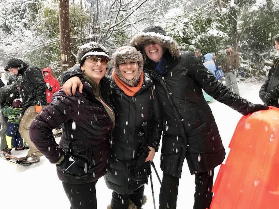 Three women sledding in the snow