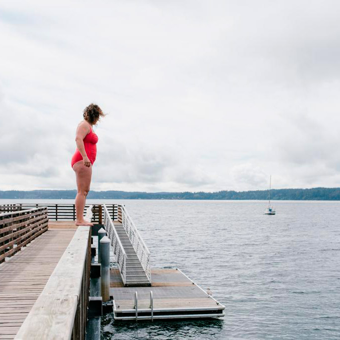 Standing on the railing of the dock, looking down at the very cold water.