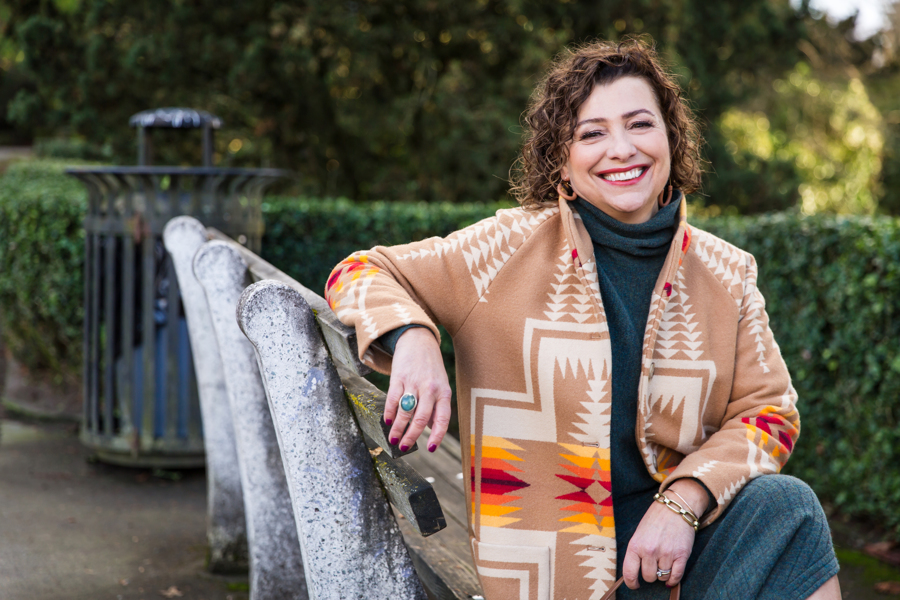 Bridget smiling seated on a park bench